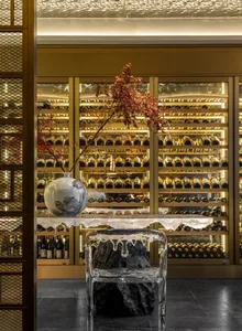 A modern wine bar with a glass and mirrored ceiling, black marble flooring, and shelves filled with wine bottles.