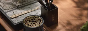 A wooden cutlery storage container with chopsticks and chopstick rest on a wooden table.