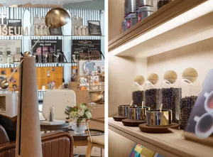 A coffee shop interior featuring metallic floor lamp, wooden chairs, and glass display cases.