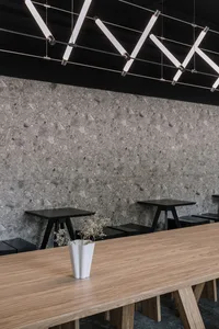 Industrial-style cafe interior with a terrazzo wall and wooden table.
