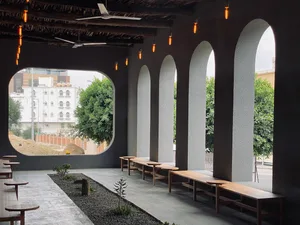 A modern industrial junction space with concrete walls, wooden benches, and hanging Edison-style light bulbs.