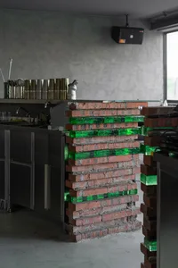 Industrial-style restaurant bar with red brick wall and green glass block structure.