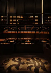 A modern, industrial-style restaurant interior with wooden flooring and booths.