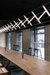 Modern cafe interior with long wooden table, metal stools, and geometric light fixtures