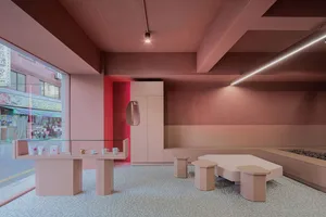 A modern cafe interior with pink and red color scheme, featuring minimal furniture and a cozy seating area.