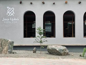 A modern coffee shop exterior featuring a minimalist design with concrete elements and large arch windows.