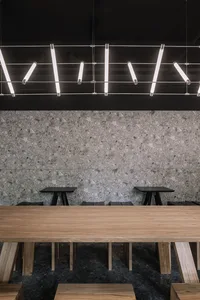 Modern coffee shop interior with concrete flooring, wooden furniture, and minimalist design.
