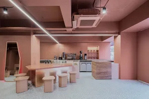 A modern coffee shop with pink walls and a central bar counter.