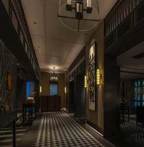 A modern industrial hallway with concrete walls and metal railings, featuring bold patterns on the floor and artistic wall de