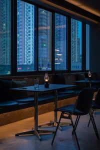 Industrial-style restaurant interior with metal tables, glass lamps, and cushioned seating.
