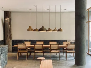 Minimalist dining room featuring wooden furniture and hanging clay lamps.
