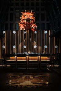 A modern bar interior with wooden accents, featuring a large red mascot statue.