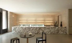 A modern cafe interior with white marble countertops, a black table, and chairs.