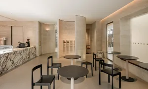 A modern coffee shop with minimalist design, featuring ceramic tiles and marble columns.