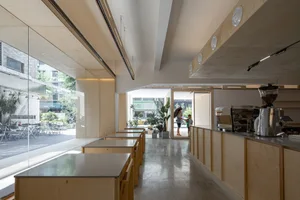 A modern minimalist coffee shop interior with wooden tables and a sleek, open design.