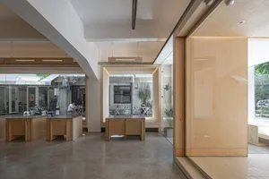 Interior of a modern office space featuring wood furniture and glass partitions.