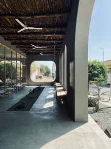 A modern patio with concrete floor, wooden benches, and natural stone planters.