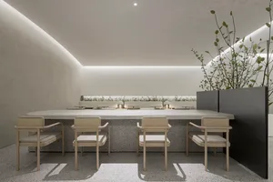 A modern restaurant interior with concrete walls and floors, featuring minimalist furniture and a serene atmosphere.
