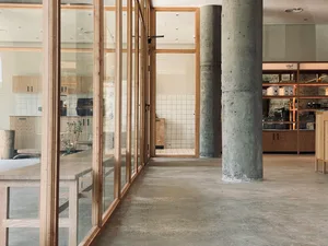 Modern restaurant interior with minimalist design, concrete floors, and wooden tables and chairs