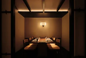 A modern restaurant dining room with a wooden table and chairs, set for dining with soft ambient lighting and minimalist deco