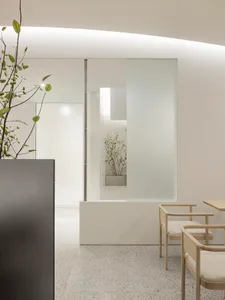A modern restaurant interior with glass partitions and minimalist furniture.