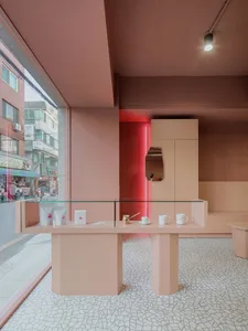 Modern retail coffee shop interior with contemporary pink and red accents and a glass counter featuring coffee-related produc