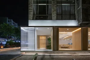 Shopfront with retractable blinds at night, showcasing a modern design with illuminated interior.