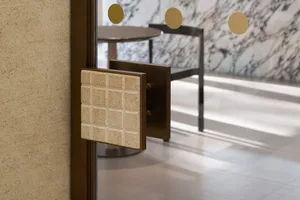 Close-up of a terrazzo-patterned glass door handle and panel.