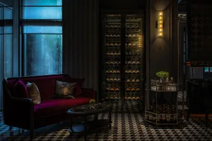 Elegant contemporary lobby with red sofa, glass wall, and wine cellar.