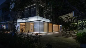 Modern restaurant exterior at night with illuminated signage and seating area.