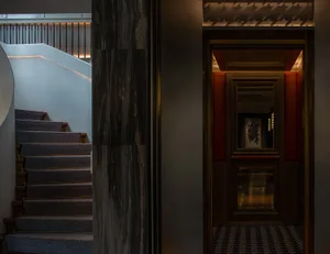 An elegant modern hotel lobby featuring black marble walls and metallic accents.