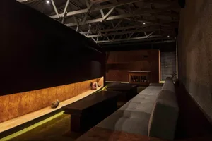 Industrial-style bar lounge area with wooden seating and metal accents on a wooden floor.