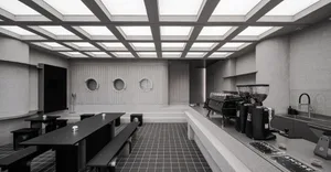 A modern coffee shop interior featuring concrete walls, glass windows, and industrial-style seating