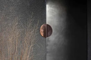 Metal door panel with circular cutout on a textured grey background.