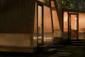 Wood panel clad exterior with glass wall and concrete accents of a minimalist residential home during nighttime with warm ind