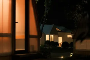 A modern residential exterior with wooden elements and white curtains.