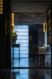 Modern restaurant interior with glass, metal, and wooden decor and lighting.