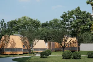 Several wooden huts arranged on a grassy area surrounded by trees.
