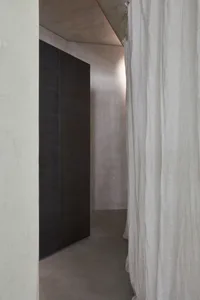 Minimalist interior space featuring concrete walls and floor, with a white curtain.