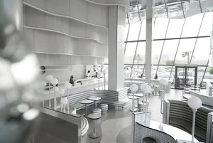 A modern, minimalist restaurant interior with metallic tile walls and a spacious, open design.