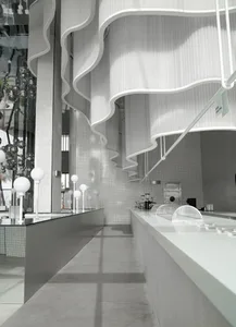 A modern bar interior featuring metallic accents, transparent glass elements, and concrete surfaces.