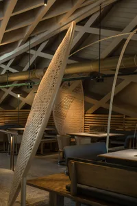 Modern restaurant interior showcasing contemporary design with wooden elements and high ceilings.