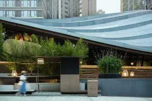 Modern restaurant exterior with metal roofing, planters, and lighting.