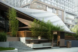 A modern urban architectural design featuring bamboo materials and a wave-shaped canopy.
