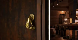 Close-up of a gold hand-shaped doorknob on a textured, wood-grain door.