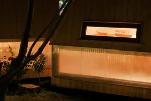 A wooden interior with a warm light emanating from within, viewed at night.