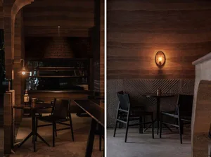 A cozy industrial cafe setting with a concrete wall and table, featuring a warm light fixture.