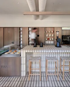 An industrial-style coffee shop interior with wooden stools, a counter, and shelves.