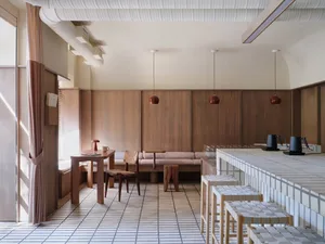 Modern cafe interior featuring wooden benches, concrete bar, and pendant lights.
