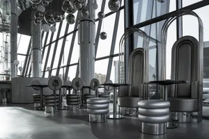 A modern restaurant interior with metallic tables and stools under hanging spherical lights, glass partition seating, and lar